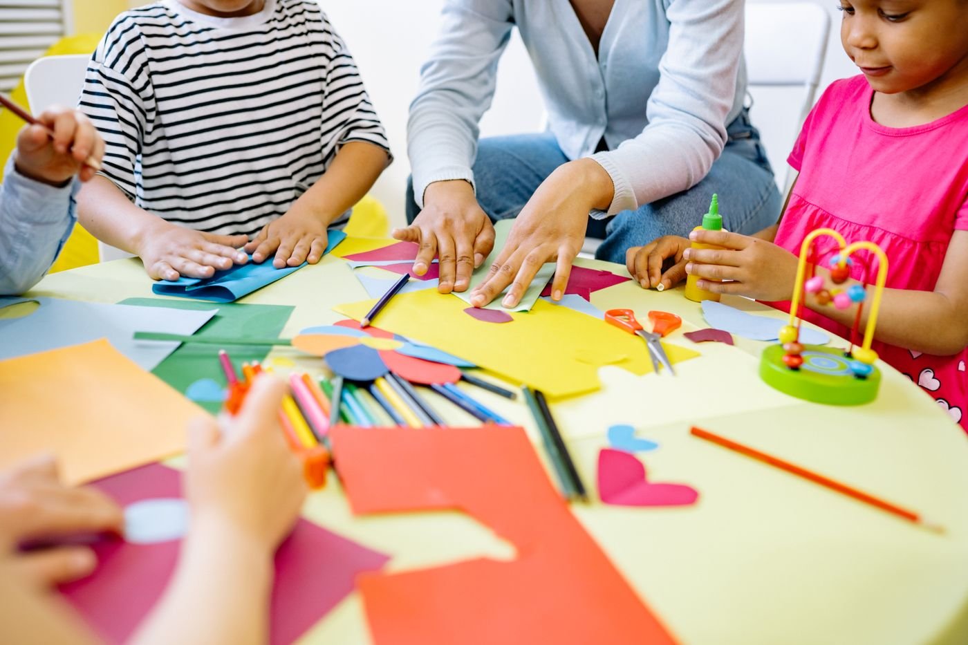 Kinder basteln gemeinsam mit buntem Papier