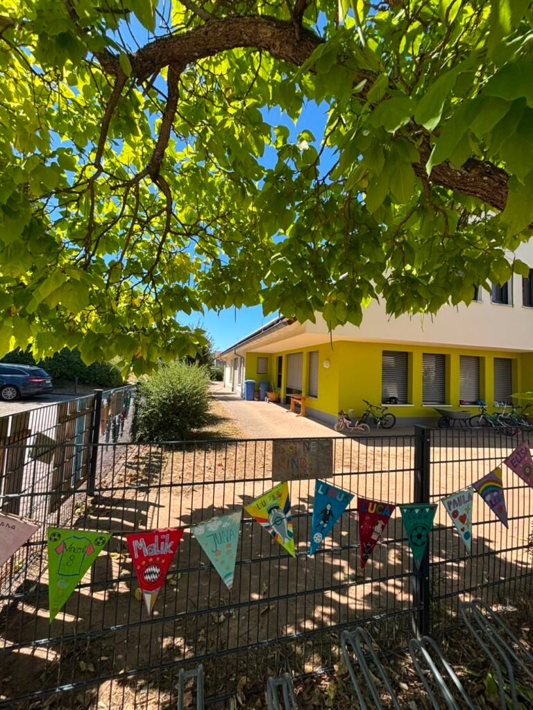 Garten des Kindergartens mit Wimpelkette und altem Baum
