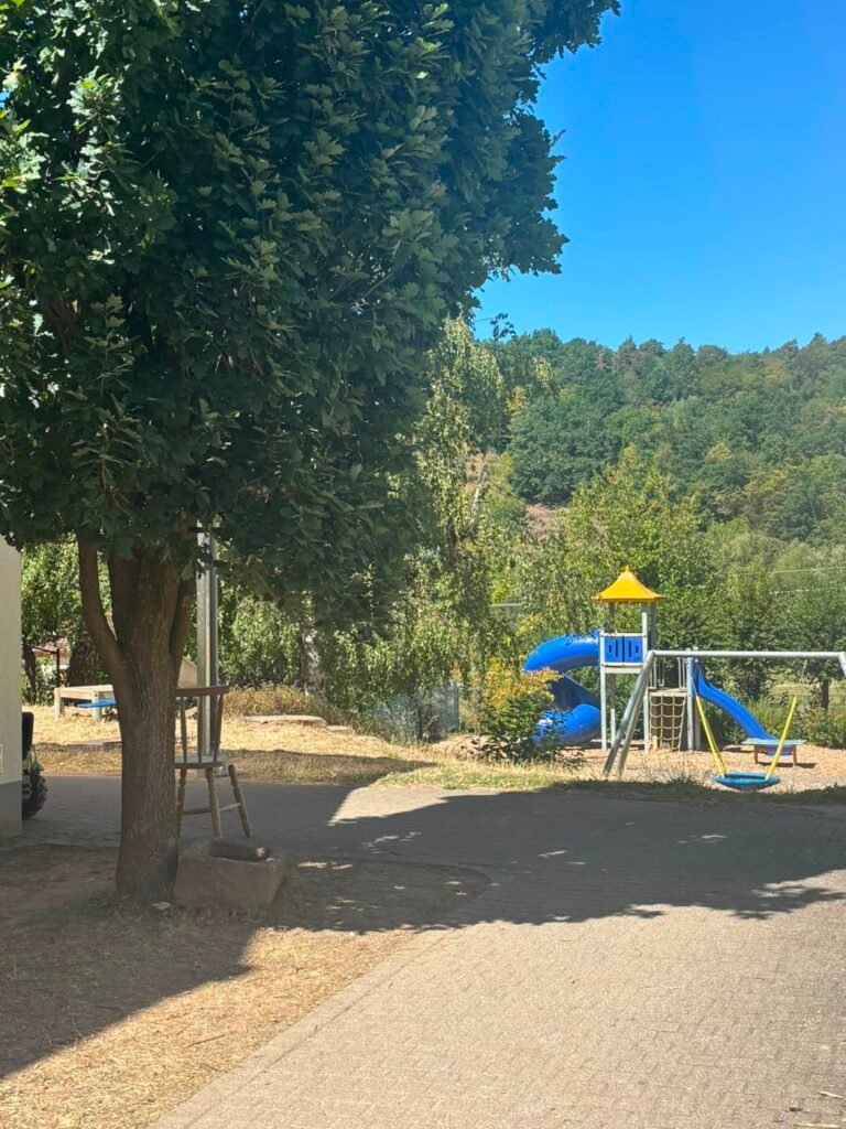 Klettergerüst mit Rutsche und Schaukel im Garten des Kindergartens