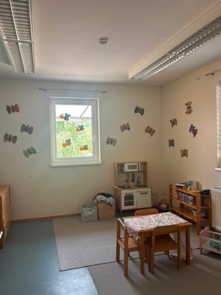 Nebenraum Regenbogenland mit Kinderküche und Schmetterlingen an der Wand