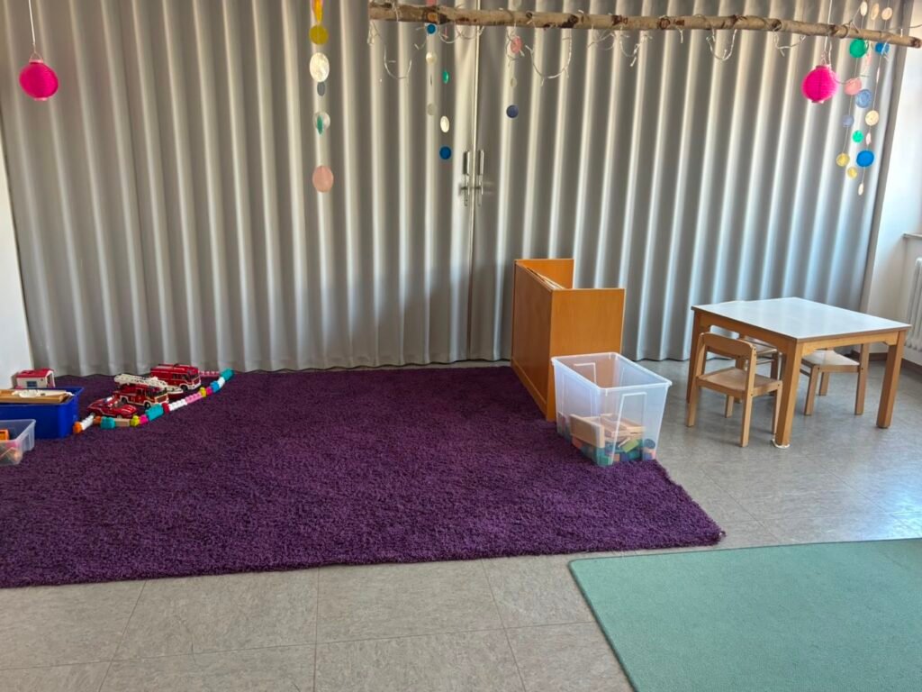 Nebenraum der Villa Sonnenschein mit Spielteppich und Basteltisch